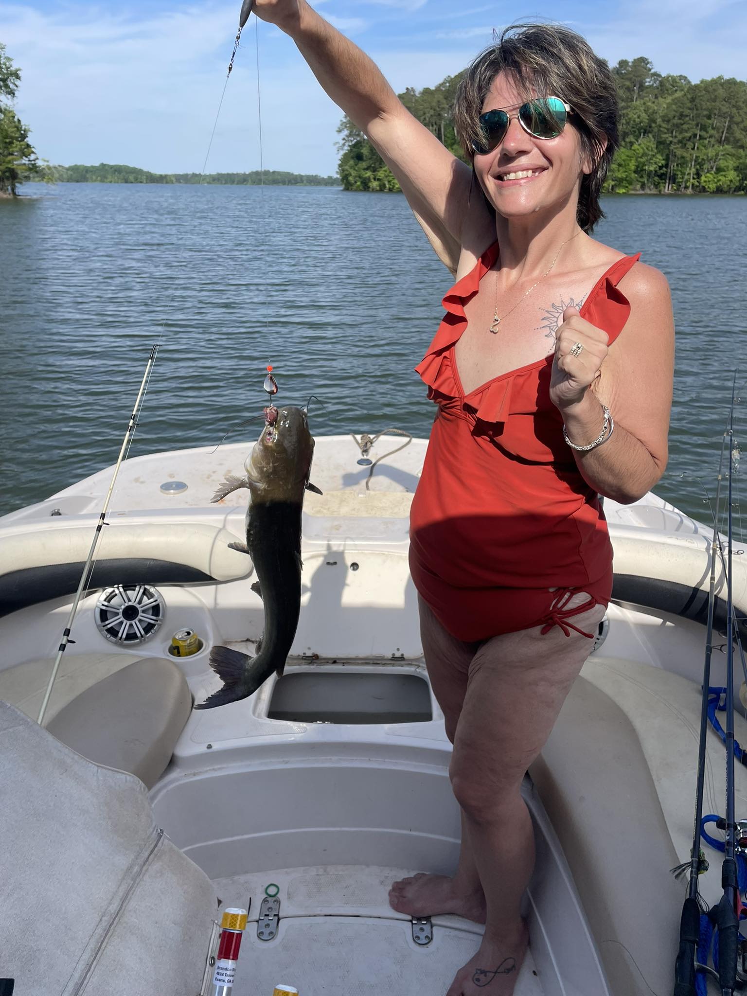 Lindsay on the boat holding up the fish she just landed on the lake.