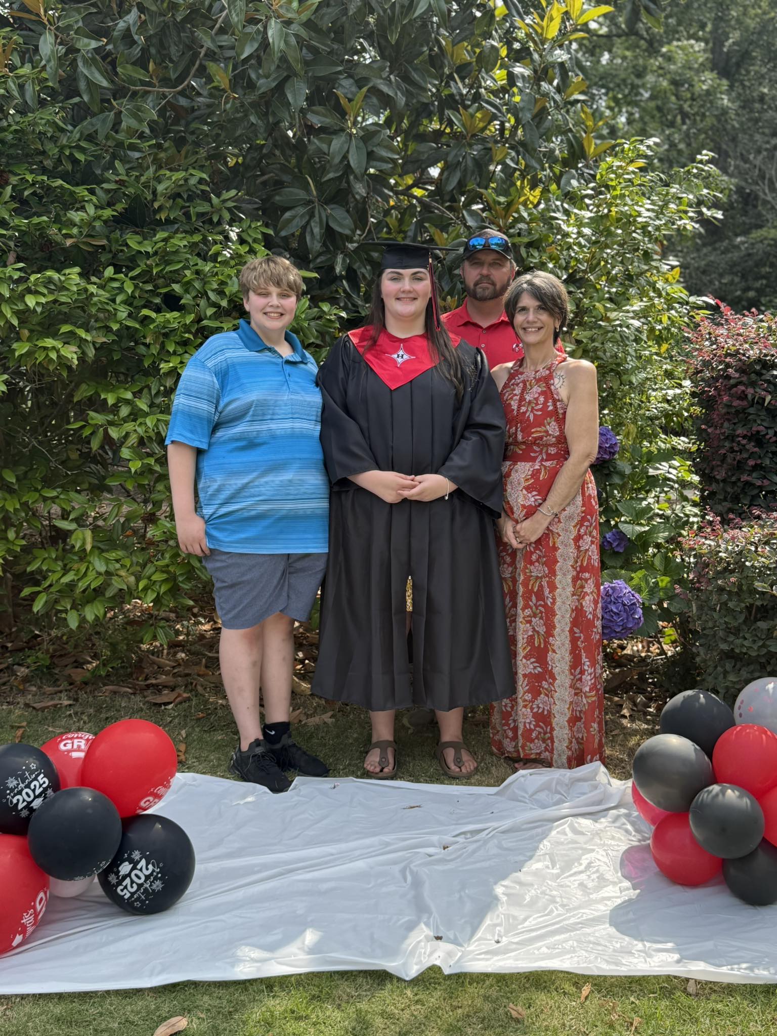 The family standing together at a graduation party, balloons underfoot.