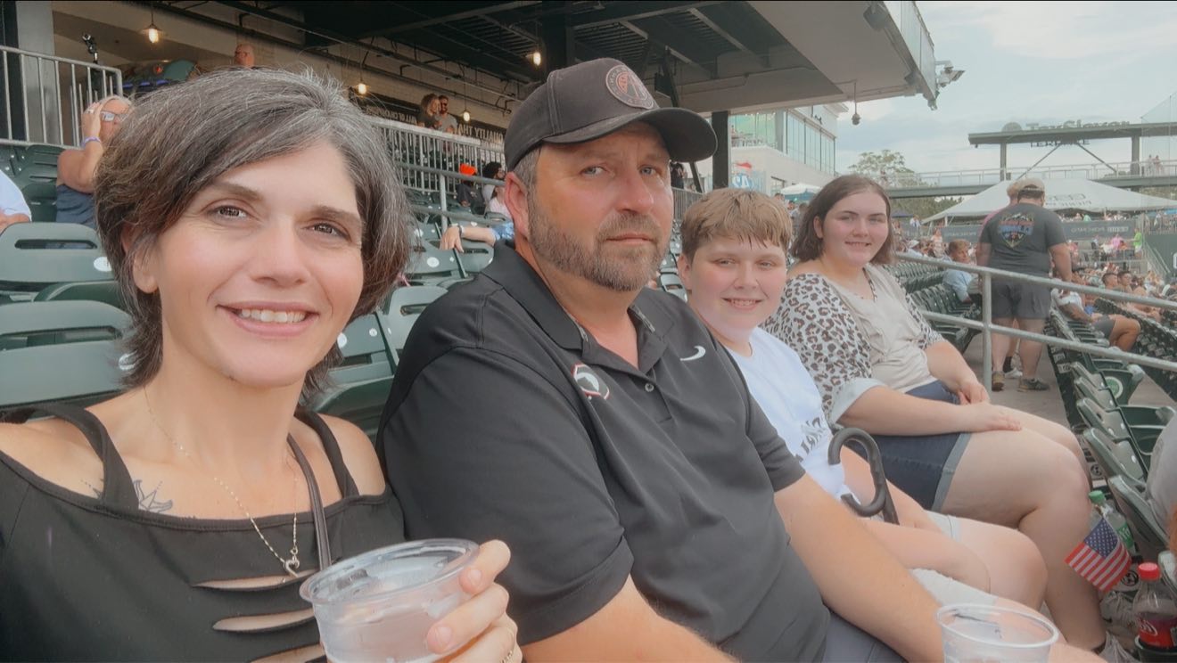 The whole crew in the stands at a ball game on a warm evening.