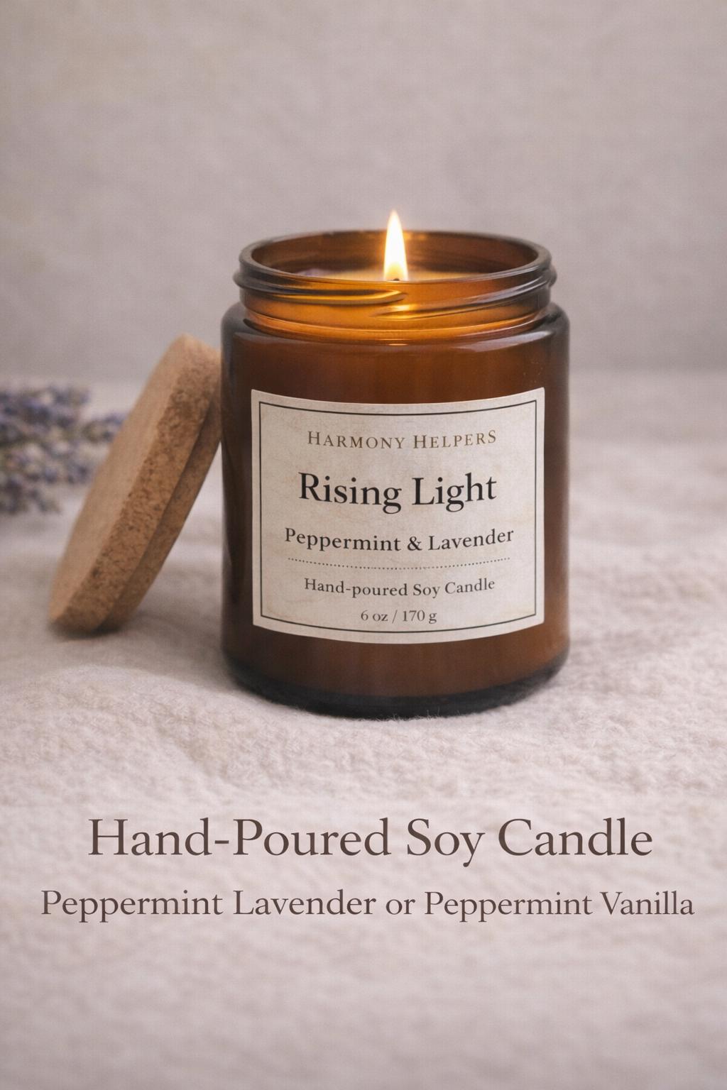 A lit Rising Light hand-poured soy candle in an amber jar with its wooden lid beside it.