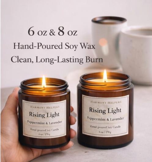 A hand holding two Rising Light soy candles, showing the 6 oz and 8 oz sizes.